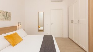 Ein Schlafzimmer mit einem Bett, einem Nachttisch, einem Spiegel, einem Kleiderschrank und einer Klimaanlage.