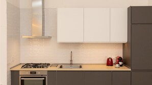 Eine moderne Küche mit Gasherd, Backofen, Spüle aus Edelstahl und einer Kaffeemaschine.