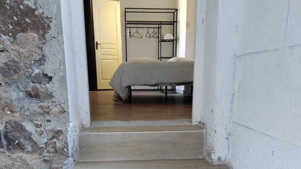 A staircase leading to a bedroom with a bed, a metal rack with clothes, and a chair. - Provencal house for 14 sleeps with private garden. Perfect for family gatherings (La Crau)