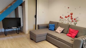 A modern living room with a grey sectional sofa, a small ottoman, and a flat-screen TV on a stand. - Provencal house for 14 sleeps with private garden. Perfect for family gatherings (La Crau)