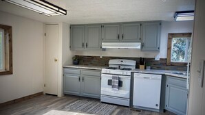 A kitchen with light blue cabinets, a white stove, and a white dishwasher. - The Man Cave. Perfect for traveling workers and a great place for families  (Greybull)