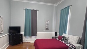 A bedroom with a bed, a TV, a dresser, and a chandelier.
