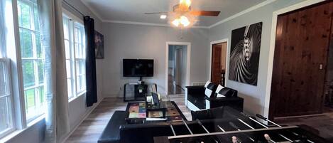 A living room with a foosball table, a television, and a ceiling fan.