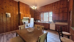 A wooden-paneled kitchen with a dining table and chairs, a chandelier, and a sign that reads "EAT WELL TRAVEL OFTEN".