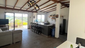 Een ruime woonkamer met een keuken, een eettafel en een bank.