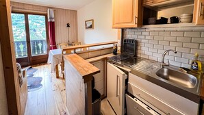 A compact kitchen with wooden cabinets, a built-in toaster, and a sink. - Comfortable studio with pool and view (Saint-Gervais-les-Bains)