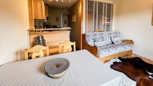 A cozy room with a wooden dining table, a patterned sofa, and a cowhide rug. - Comfortable studio with pool and view (Saint-Gervais-les-Bains)