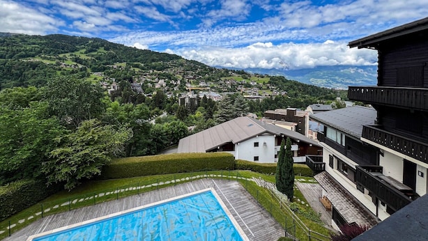 A pool area with a view of a town and mountains in the background. - Comfortable studio with pool and view (Saint-Gervais-les-Bains)