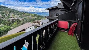A wooden balcony with a view of a village and mountains. - Comfortable studio with pool and view (Saint-Gervais-les-Bains)