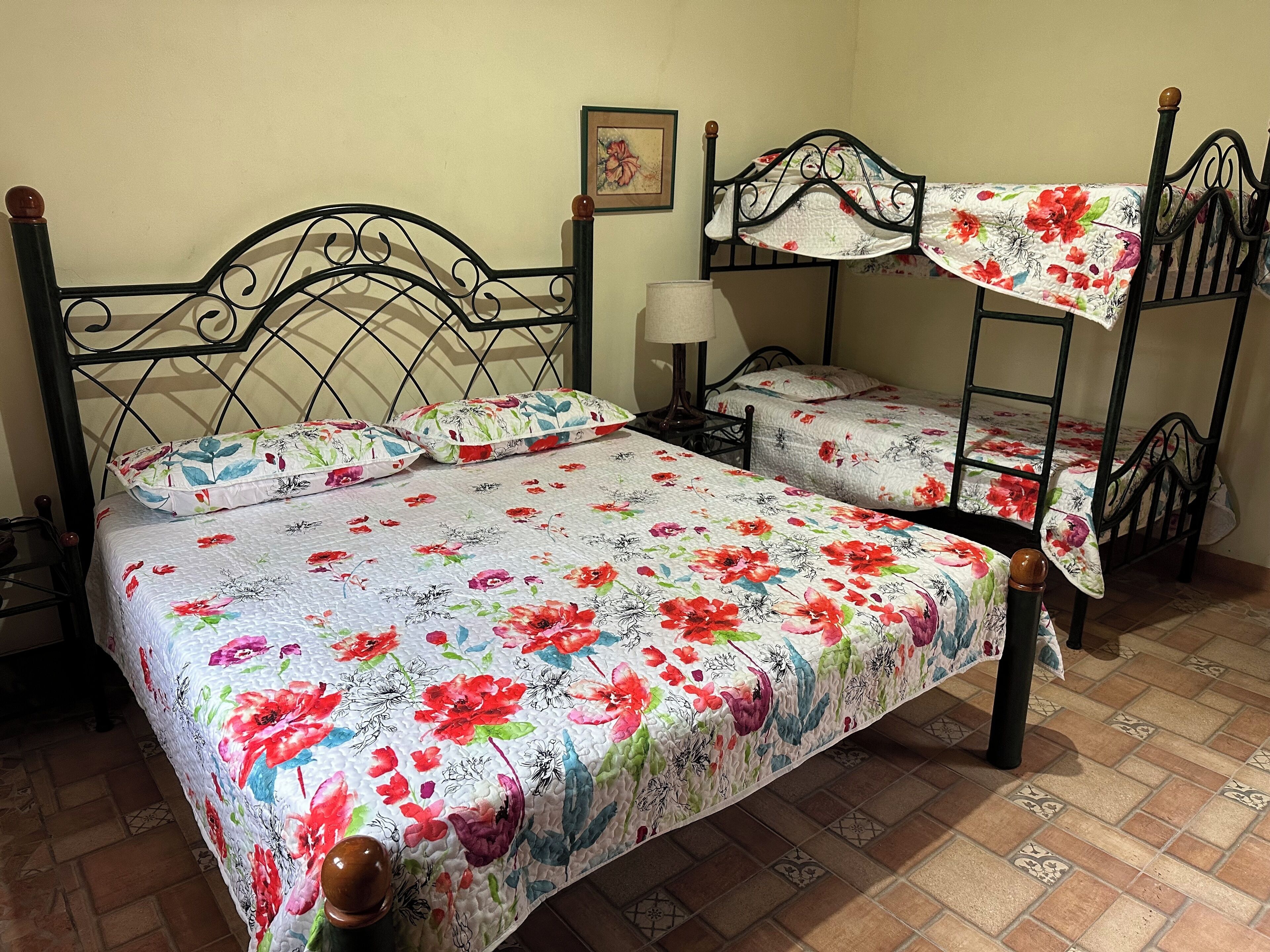 A room with two bunk beds, a single bed, and a nightstand with a lamp.