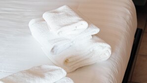 A hotel room with a neatly made bed, a visible mattress, and a rolled-up towel on the bed. - Locanda Da I Baldi (Laveno Mombello)