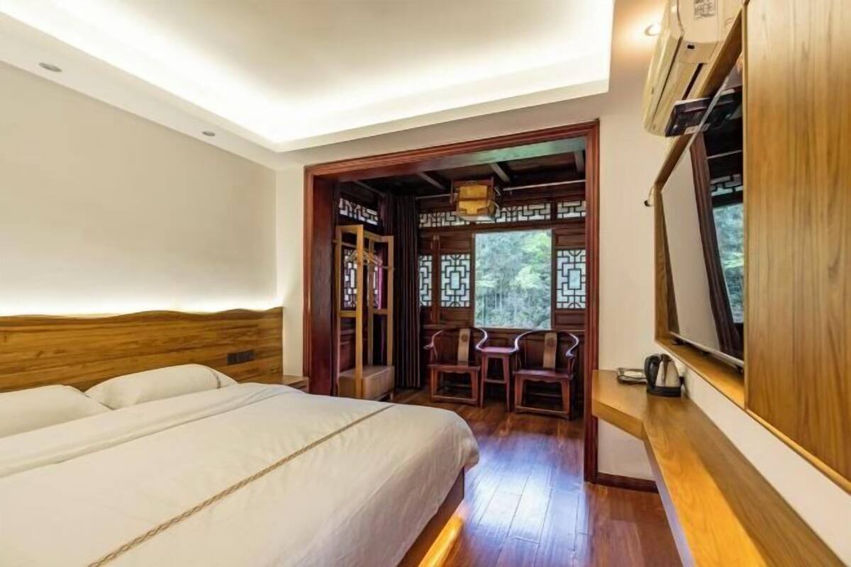 A bedroom with a bed, wooden headboard, and a small desk with chairs.