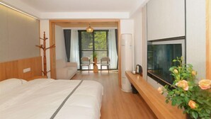 A modern hotel room with a bed, a TV, a desk, and a view of the outdoors. - Shanlin Holiday Hotel (Chongqing)