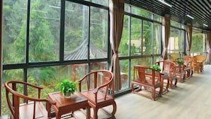 A room with large windows, wooden chairs, and a potted plant. - Shanlin Holiday Hotel (Chongqing)