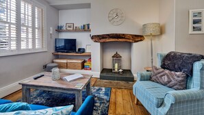 A cozy living room with a fireplace, a television, and a comfortable seating area. - The Gull's Nest (Whitby)