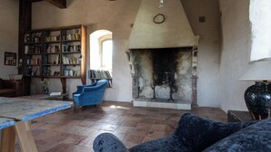 Ein gemütlicher Raum mit Kamin, Bücherregal und blauem Sessel.