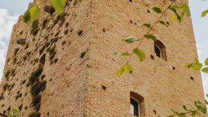 Ein hoher Backsteinturm mit zahlreichen Fenstern und Zinnen.