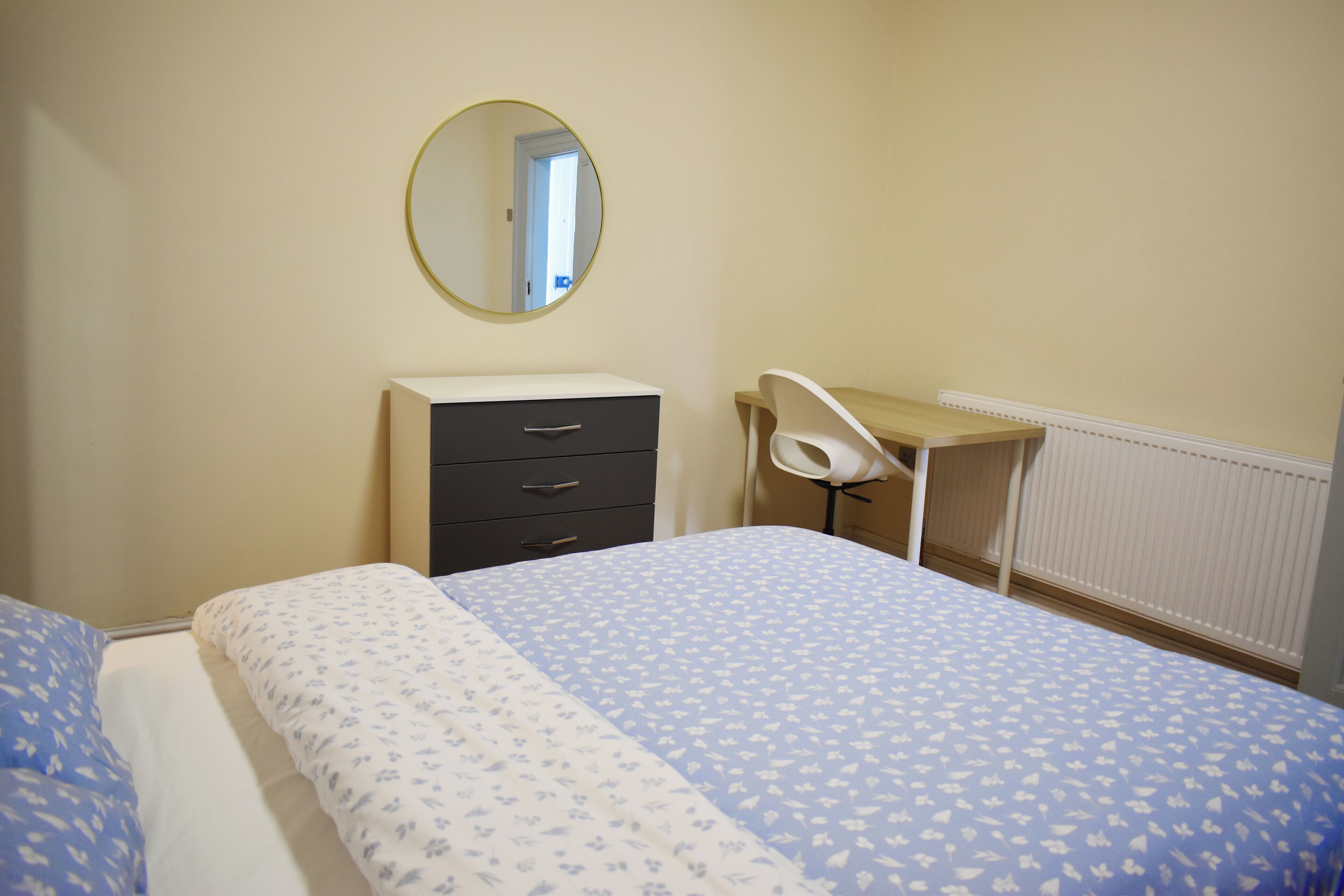 Une chambre à coucher avec un lit, une commode, un bureau et une chaise.
