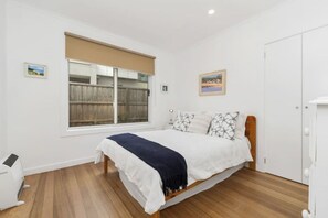 A bedroom with a bed, a window, a radiator, and a door.