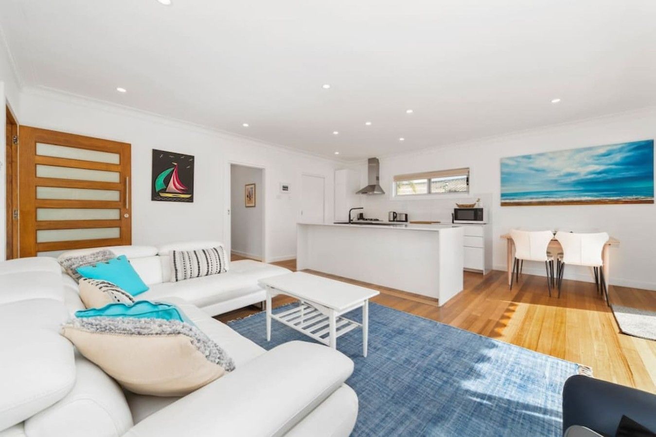 A modern living room with a sofa, a coffee table, and a dining area with a table and chairs.