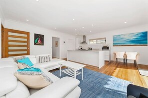 A modern living room with a sofa, a coffee table, and a dining area with a table and chairs.