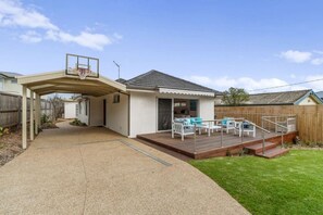 A residential property with a covered patio, a wooden deck, and a swimming pool.
