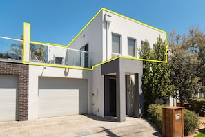 Stylish two-story residence with a clean design, surrounded by lush greenery and a well-manicured lawn.
