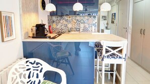 A modern kitchen with a central island, pendant lights, and a tiled backsplash. - Balcis Apartment by Hello Homes Sitges (Sitges)