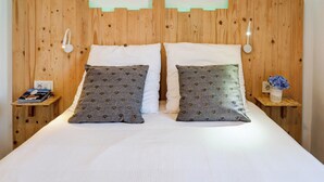 A bed with two pillows, a bedside table with a book, and a small vase with flowers. - Balcis Apartment by Hello Homes Sitges (Sitges)