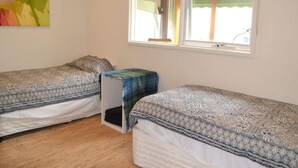 A room with two beds, a window, and a colorful painting on the wall.