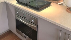 A compact kitchen with a built-in oven, a stovetop, and a kettle.
