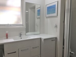 A bathroom with a white sink, mirror, and cabinets. - Rustic Rye Beach House (Rye)