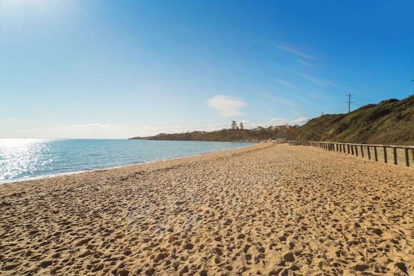 Enjoy a serene beach experience with access to the ocean and a scenic hillside view.