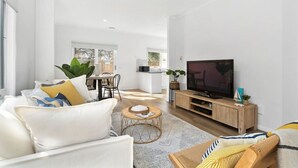 Una sala moderna con sofá, mesa de centro y mueble para televisión.