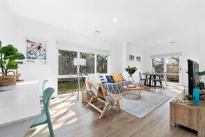 Relax in this stylish living area with a comfortable sofa, dining table, and mounted TV.