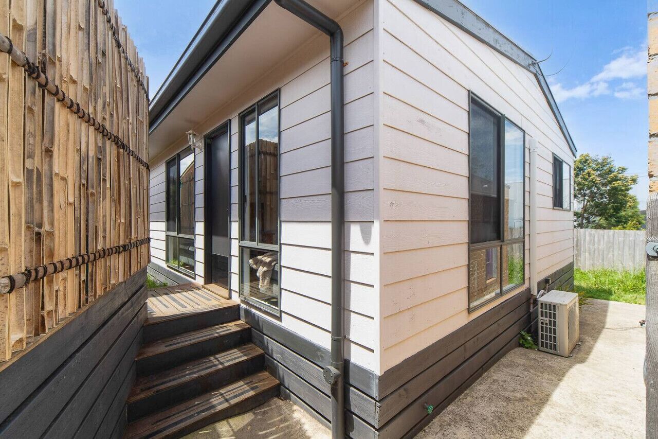 A single-story mobile home with a front porch, a small set of steps, and a side entrance.