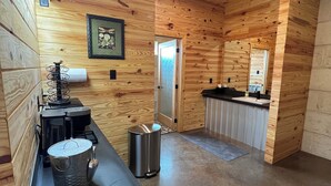 A modern kitchen with wooden walls, a countertop, a coffee machine, a trash can, and a sink.