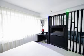 A hotel room with a bed, a desk, a TV, and a partition with vertical slats. - Watermelon Hotel (Dalian Zhongshan Square Railway Station Store) (Dalian)