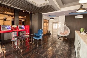 Un hall d’entrée moderne avec un comptoir d’accueil, un fauteuil bleu, un fauteuil suspendu et un sol carrelé.