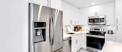 A modern kitchen with stainless steel appliances, including a refrigerator, microwave, and stove.