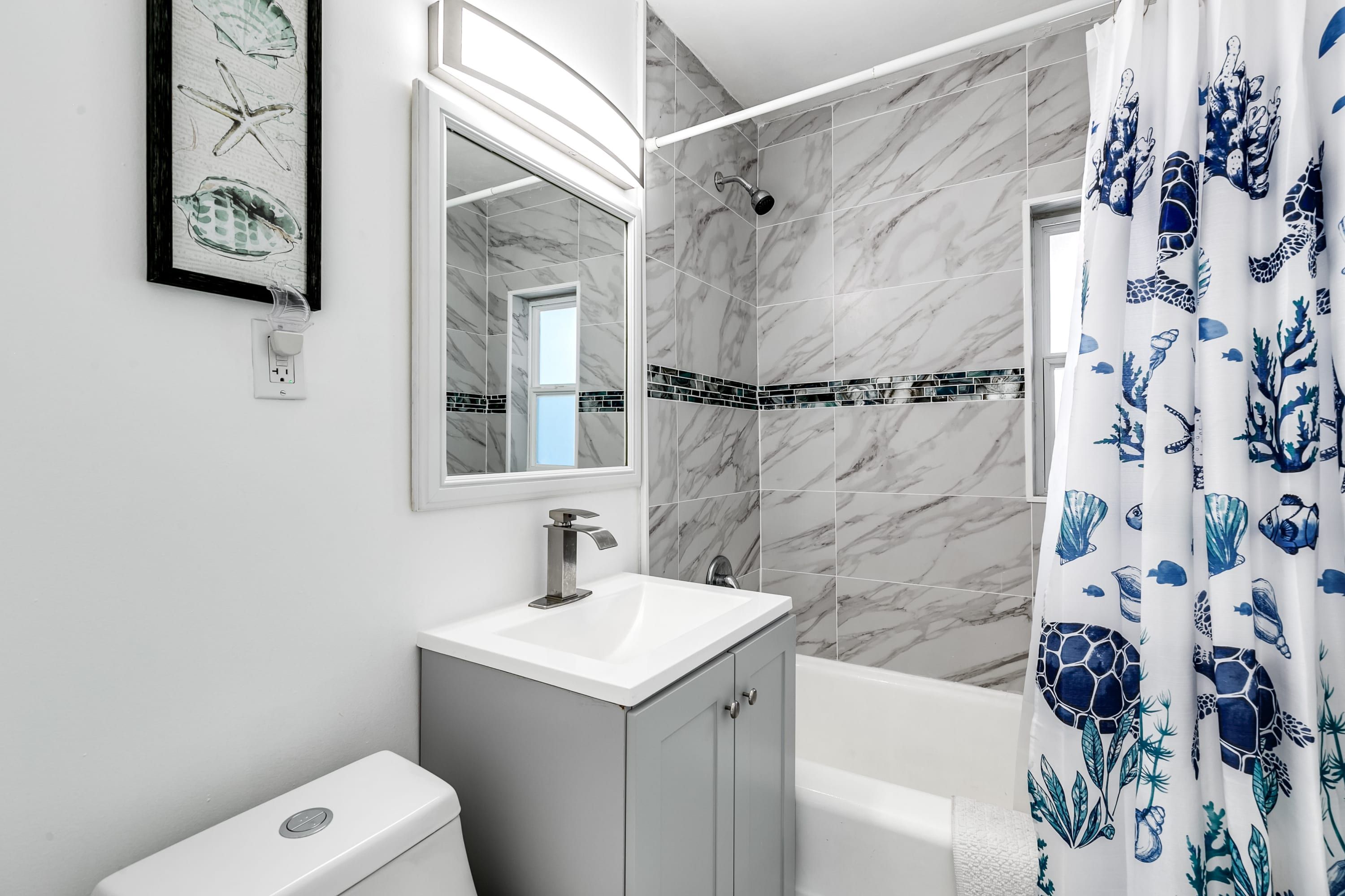 Un baño con lavamanos blanco, espejo, ducha e inodoro.
