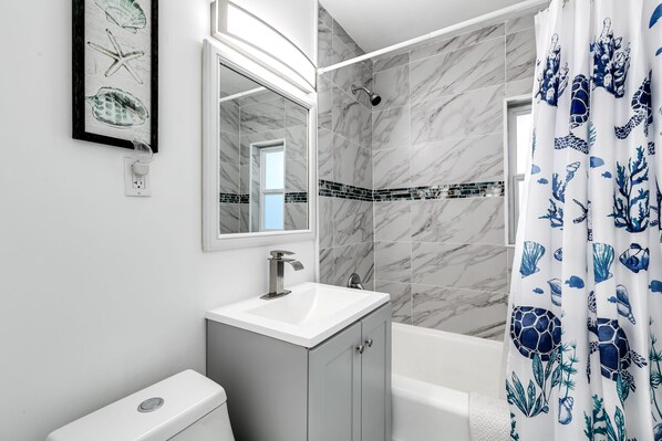 A bathroom with a white sink, a mirror, a shower, and a toilet. - Bungalow with large backyard, 5 min from beach (Pompano Beach)