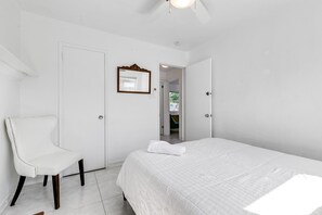 Quarto com cama, cadeira, porta e espelho.