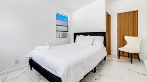 Une chambre à coucher avec un lit, une chaise, une porte en bois et une fenêtre donnant sur un paysage agréable.