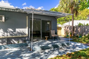 A house with a covered patio, a chair, and a small table.