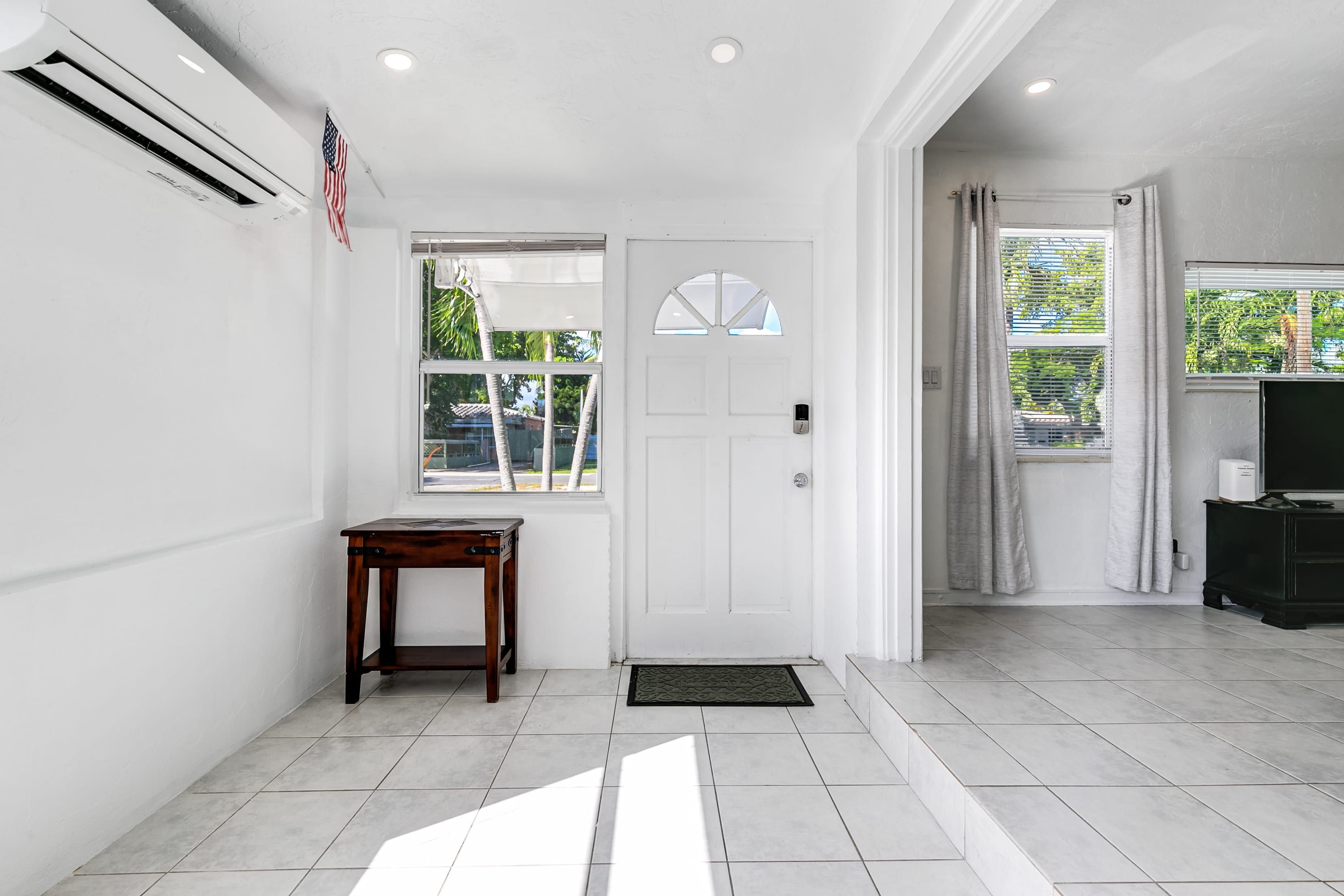 A clean, modern interior with a white door, a small wooden table, and a tiled floor.