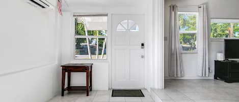 A clean, modern interior with a white door, a small wooden table, and a tiled floor.