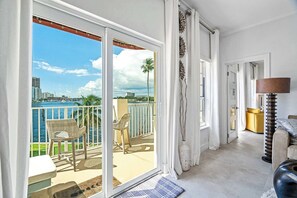 A balcony with a view of the sea and cityscape, a wicker chair, a sofa, and a lamp. - Walk to Ft Lauderdale beach - Water Views & Pool (Fort Lauderdale)
