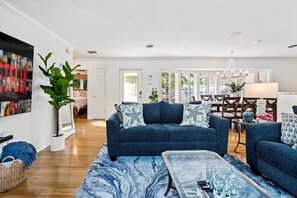 Een woonkamer met een blauwe bank, een salontafel en een grote plant.