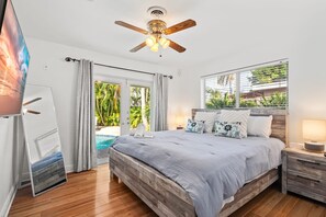 A bedroom with a wooden bed, a ceiling fan, a window with blinds, and a view of a pool. - Cypress Cove - HTD pool near Lauderdale By The Sea (Fort Lauderdale)